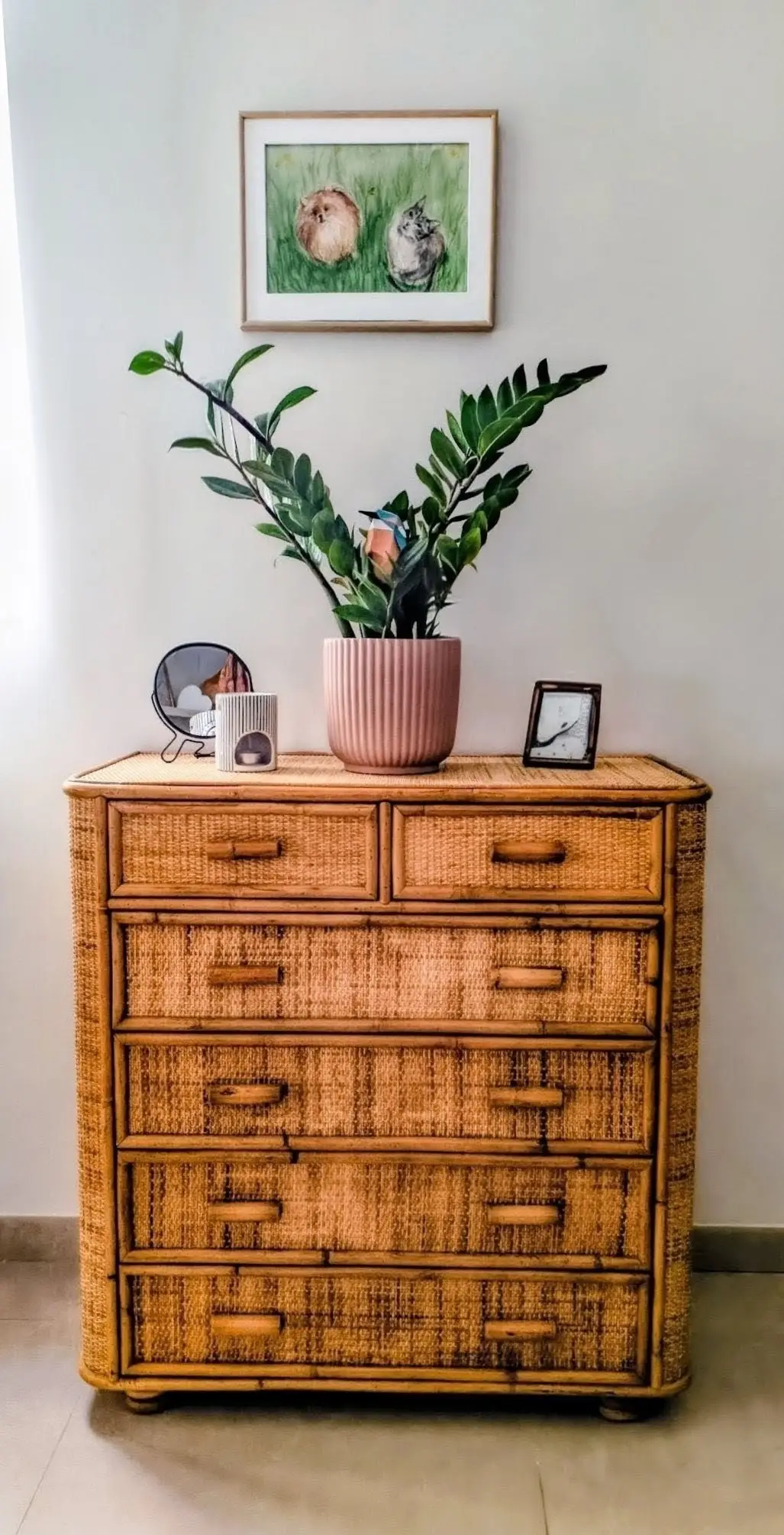 Rincón con planta, mueble de fibras naturales y cuadro botánico